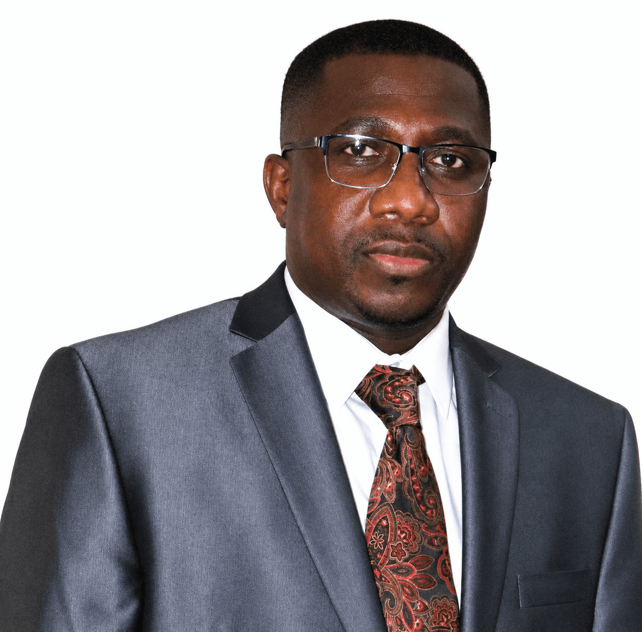 Black man wearing glasses, a grey suit, and a red patterned tie against white background.